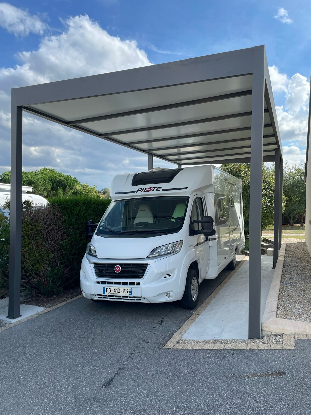Camping-car blanc sous abri métallique moderne.