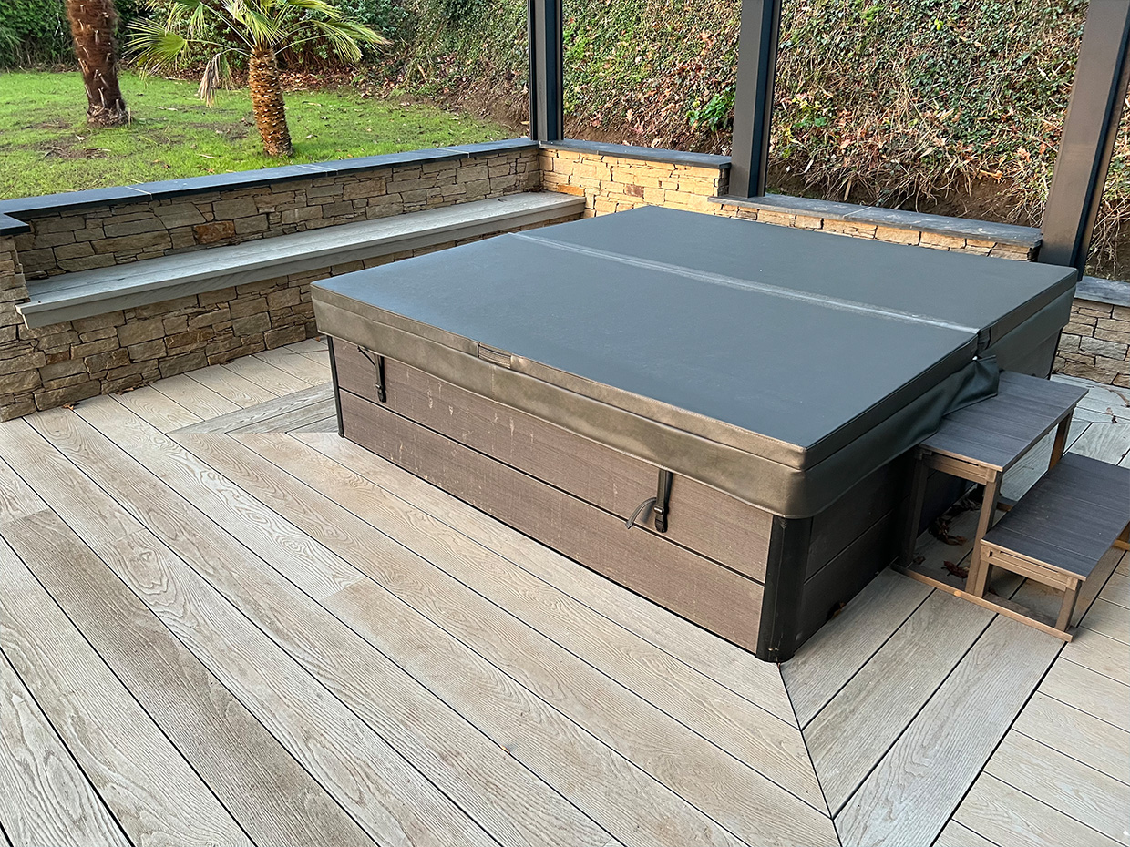Jacuzzi extérieur fermé sur terrasse en bois.