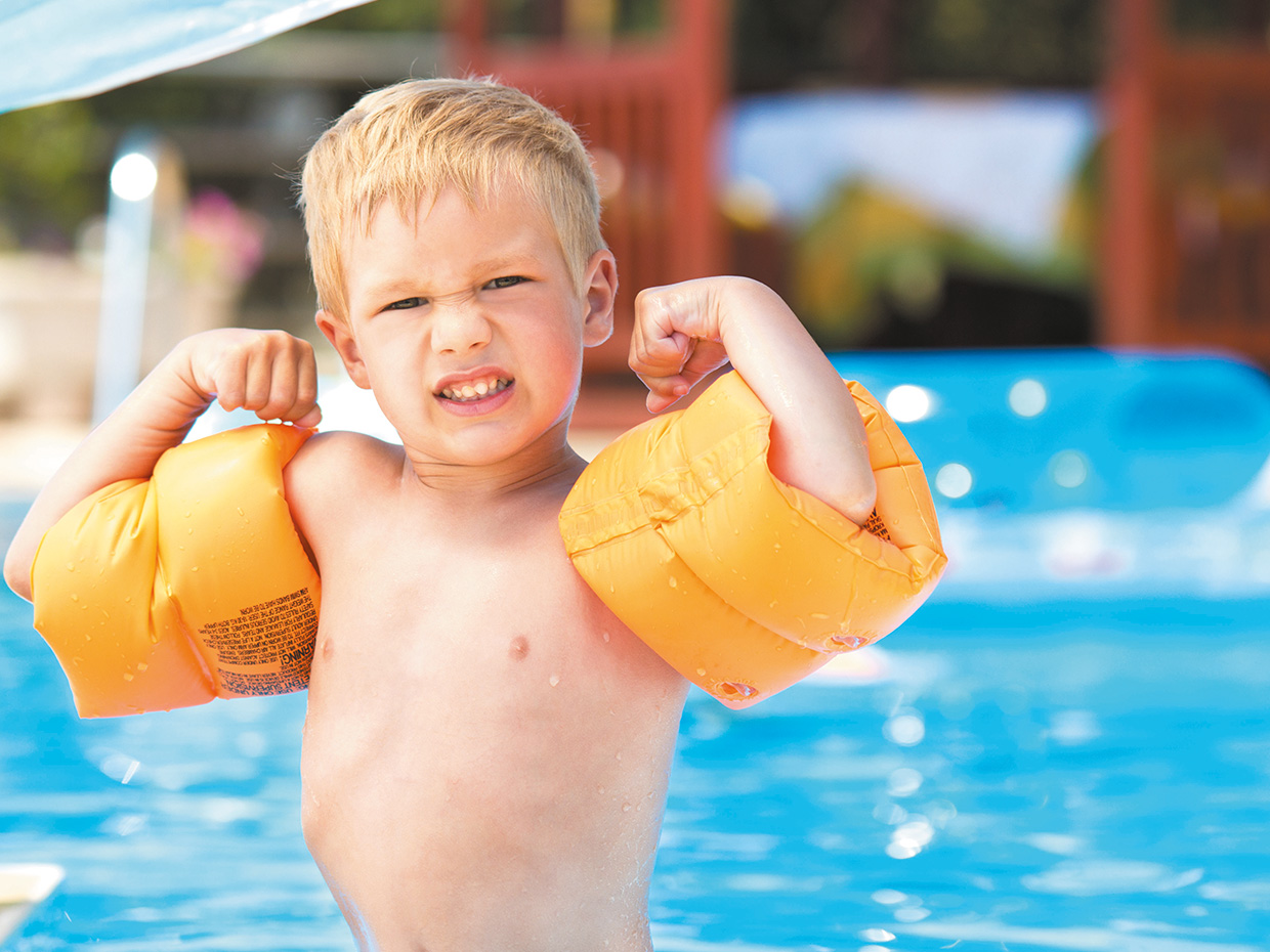 Enfant avec brassards près de la piscine