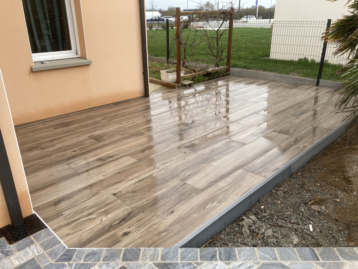 Terrasse en bois pluvieuse avec bordure en pierre.