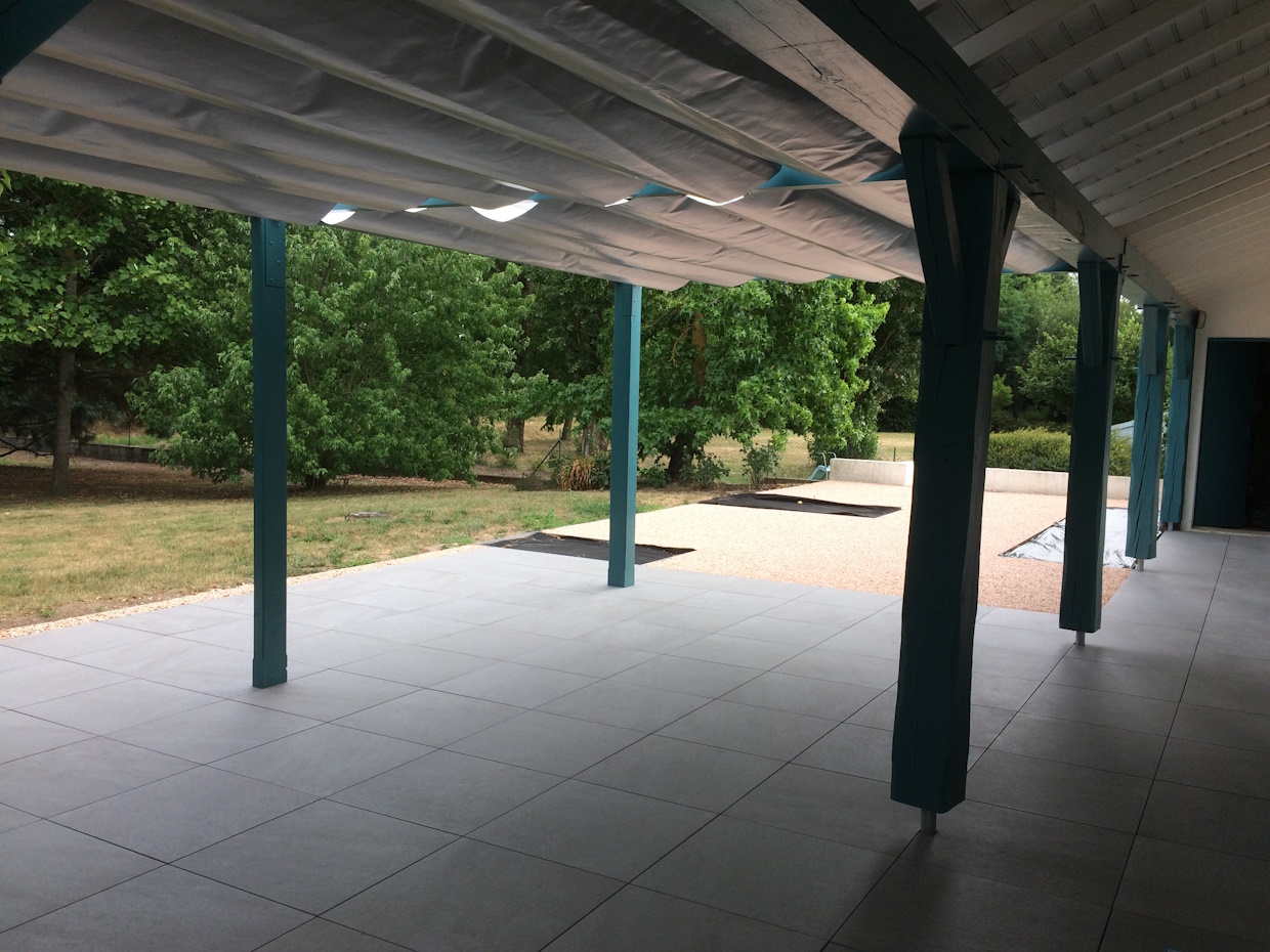 Terrasse extérieure avec colonnes et jardin.