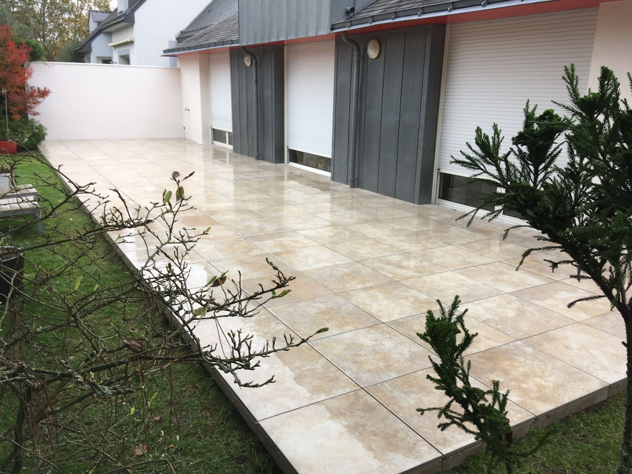 Terrasse extérieure carrelée avec jardin.