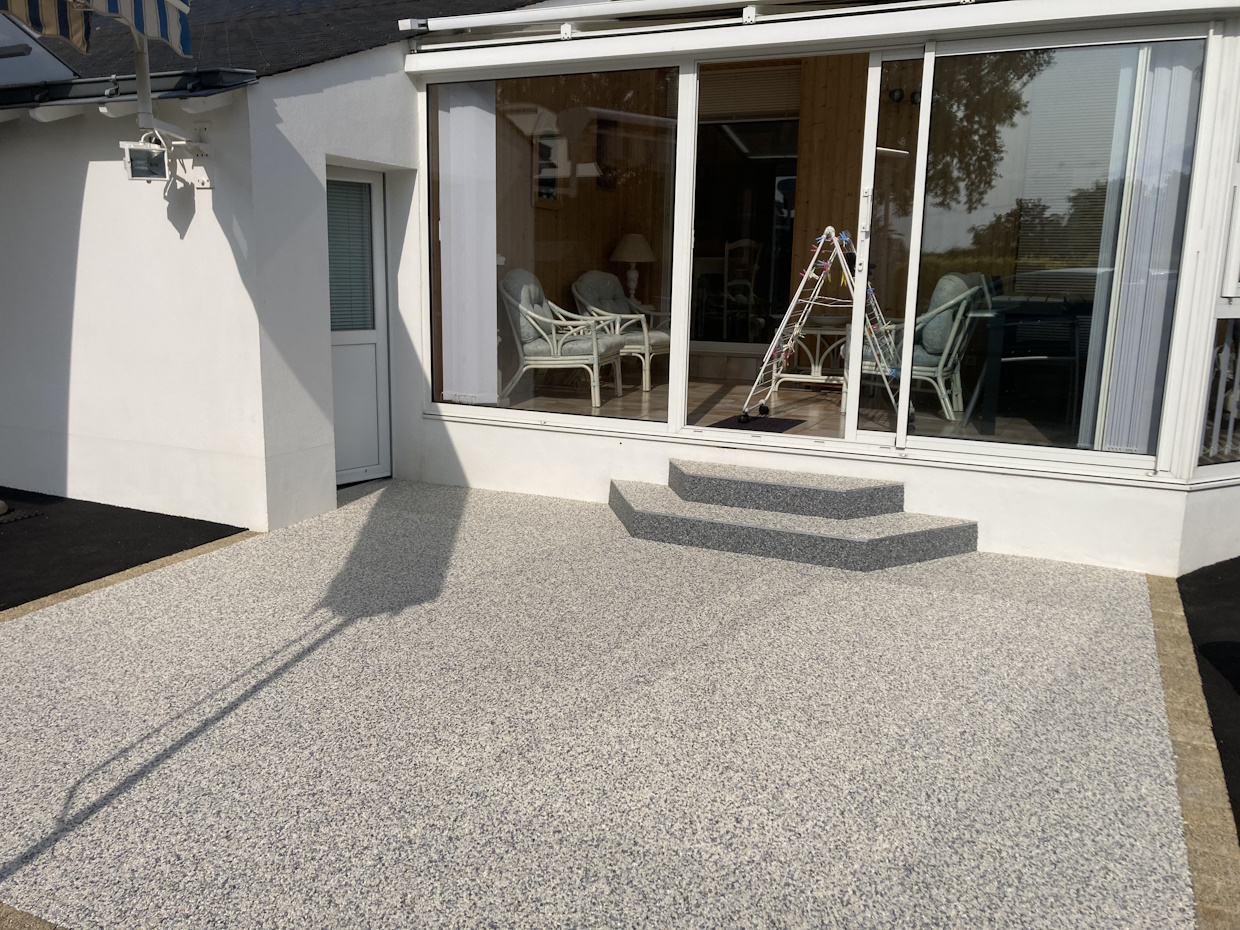 Terrasse extérieure avec baie vitrée et mobilier.