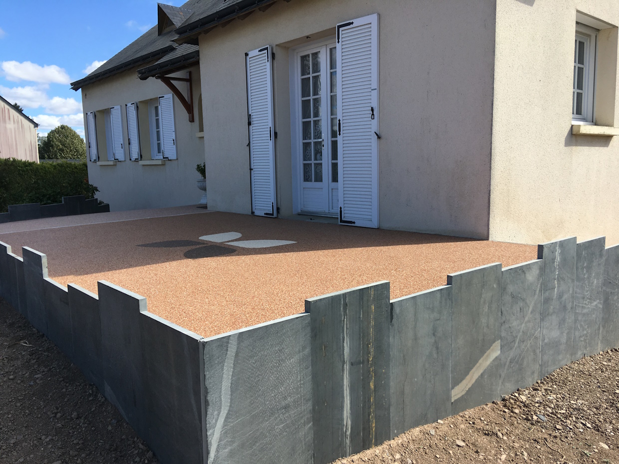 Maison avec terrasse et volets blancs.
