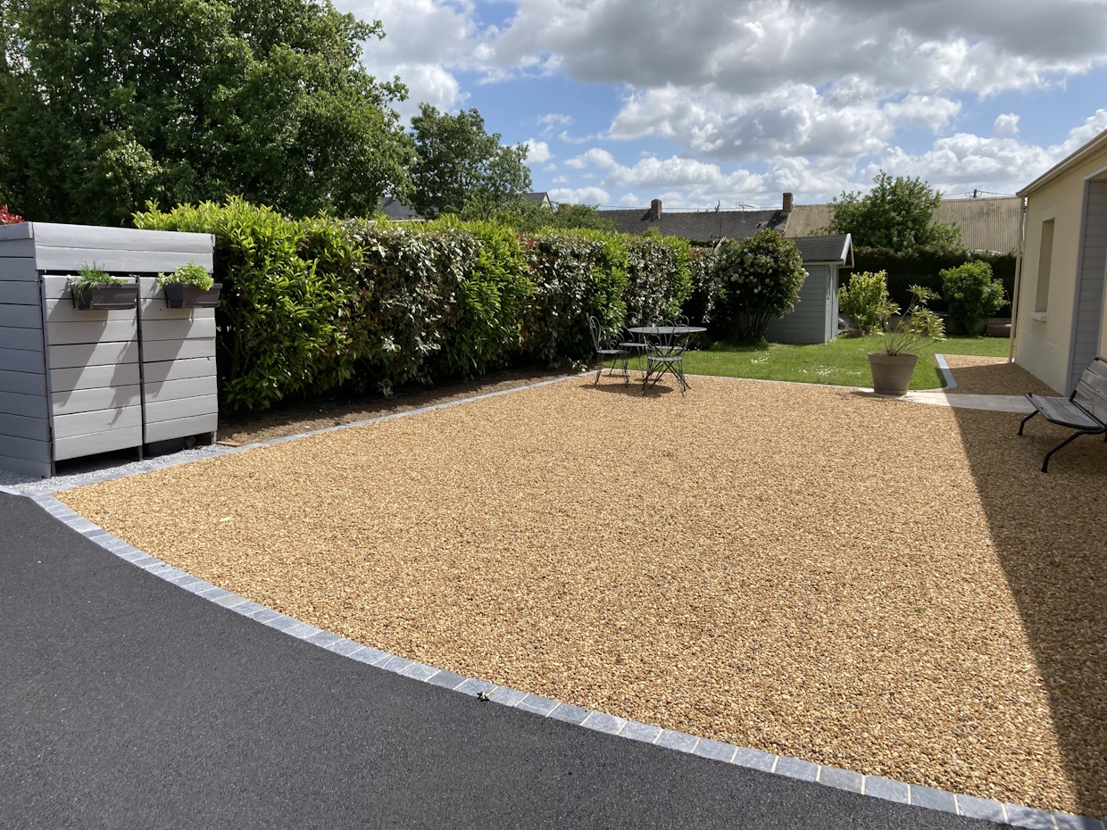 Jardin paisible avec gravier et mobilier extérieur.