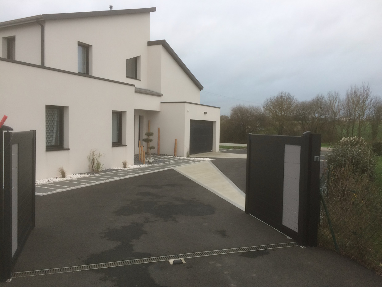 Maison moderne avec allée et portail automatique.