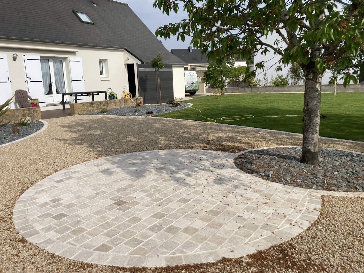 Jardin moderne avec allée pavée et pelouse verte.