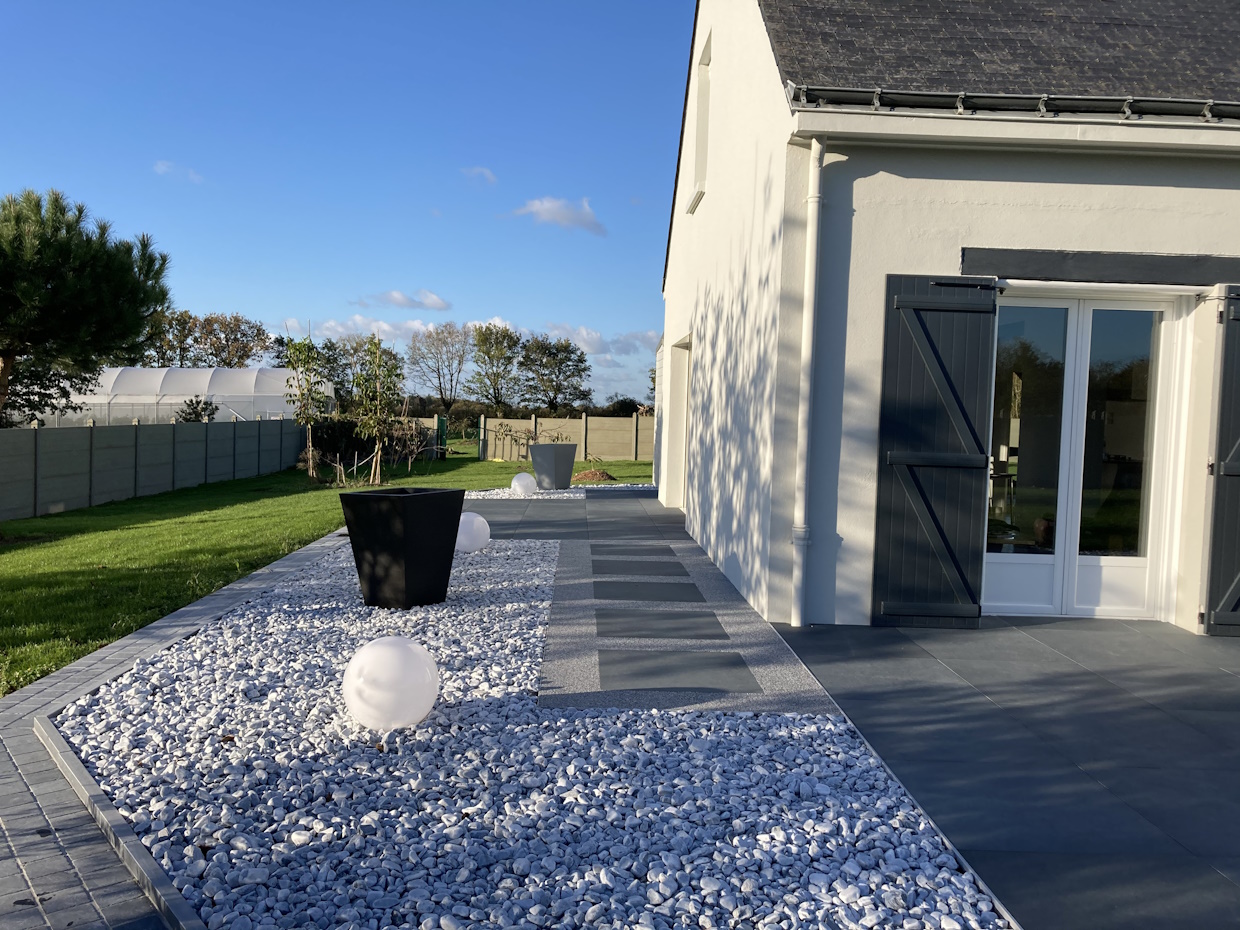 Jardin moderne avec terrasse et galets décoratifs.