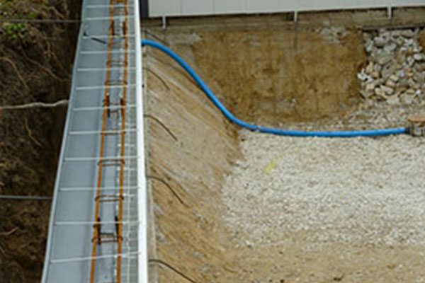 Fondations construction avec conduite bleue et armatures métalliques.