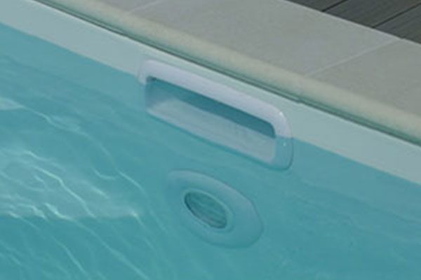 Bord de piscine moderne avec échelle et éclairage intégré.