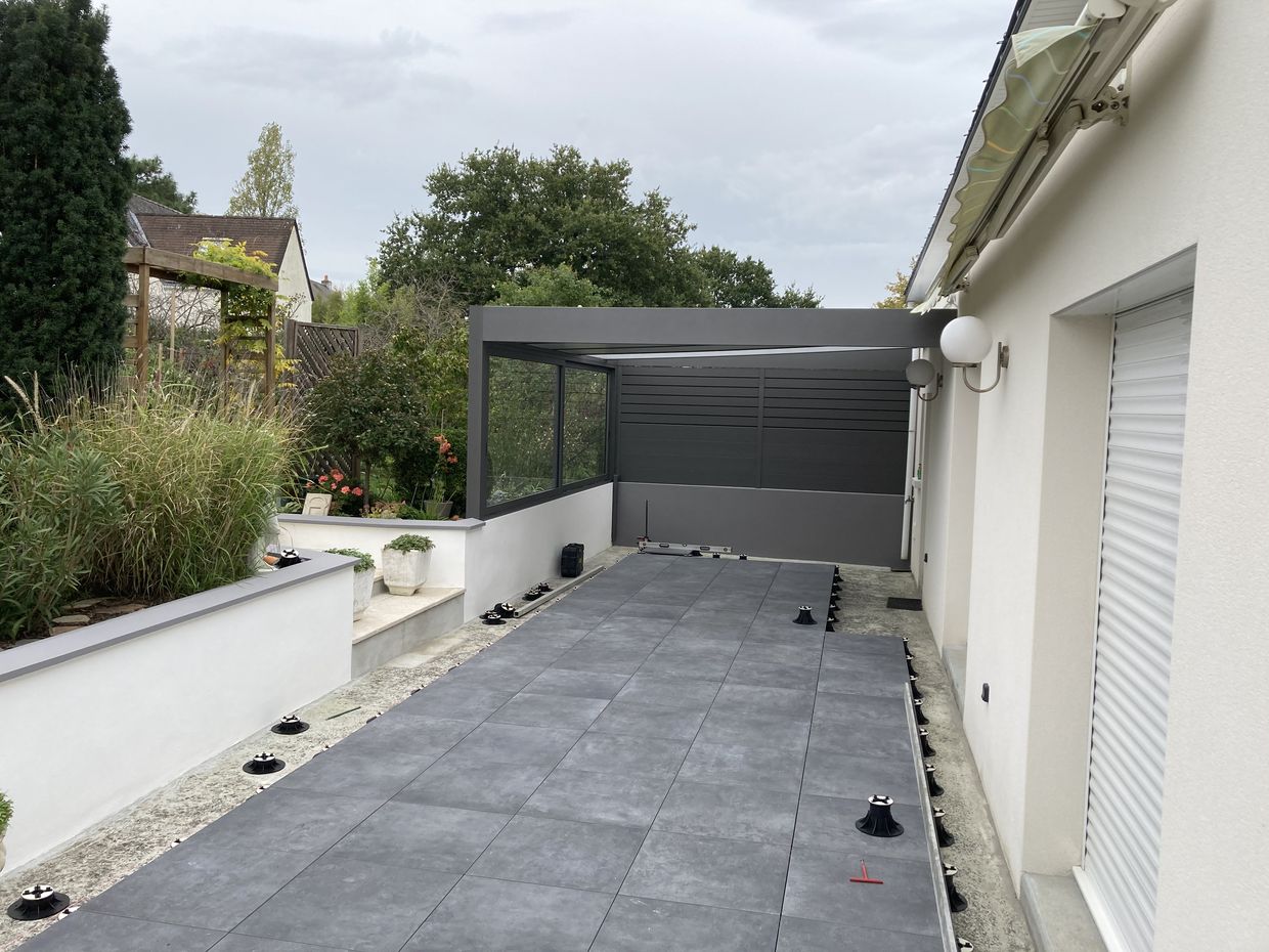Terrasse moderne avec jardin et pergola en arrière-plan.