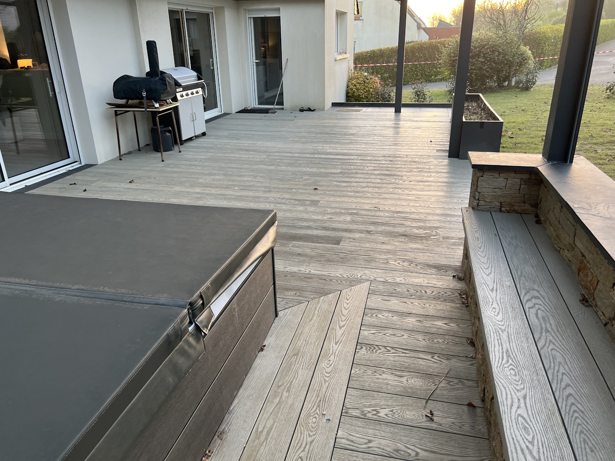 Terrasse en bois avec barbecue et mobilier de jardin.