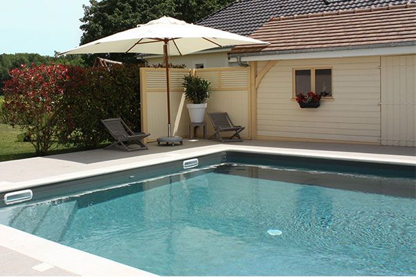 Jardin avec piscine, parasol et transats ensoleillés