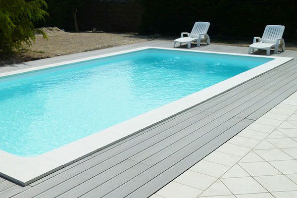 Piscine extérieure avec chaises longues et terrasse en bois.