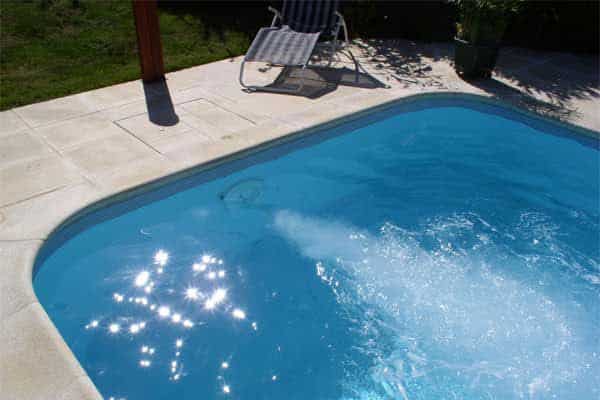 Piscine extérieure ensoleillée et chaise longue.