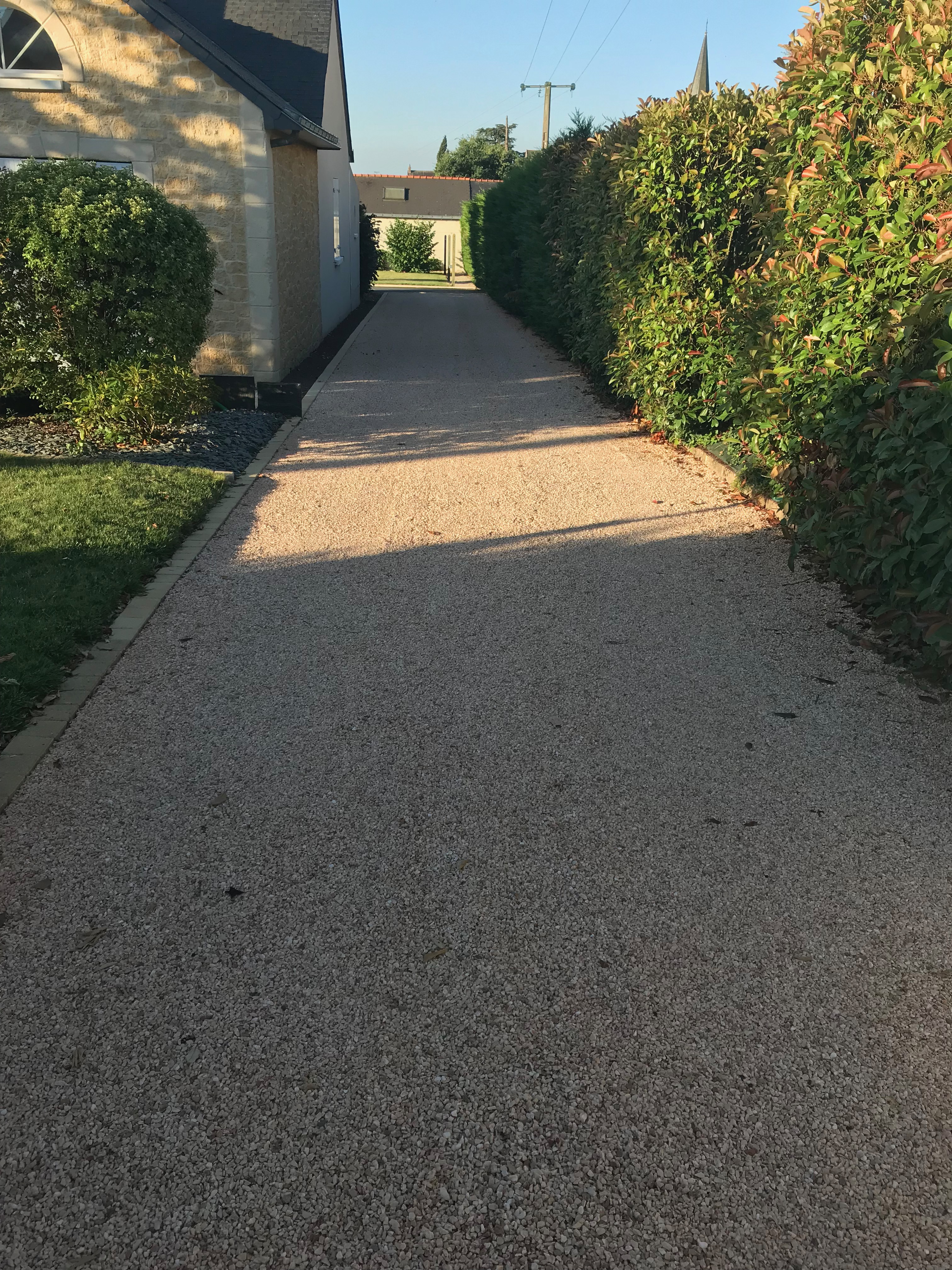 img 1068 Allée gravillonnée résidentielle avec haies et ciel bleu