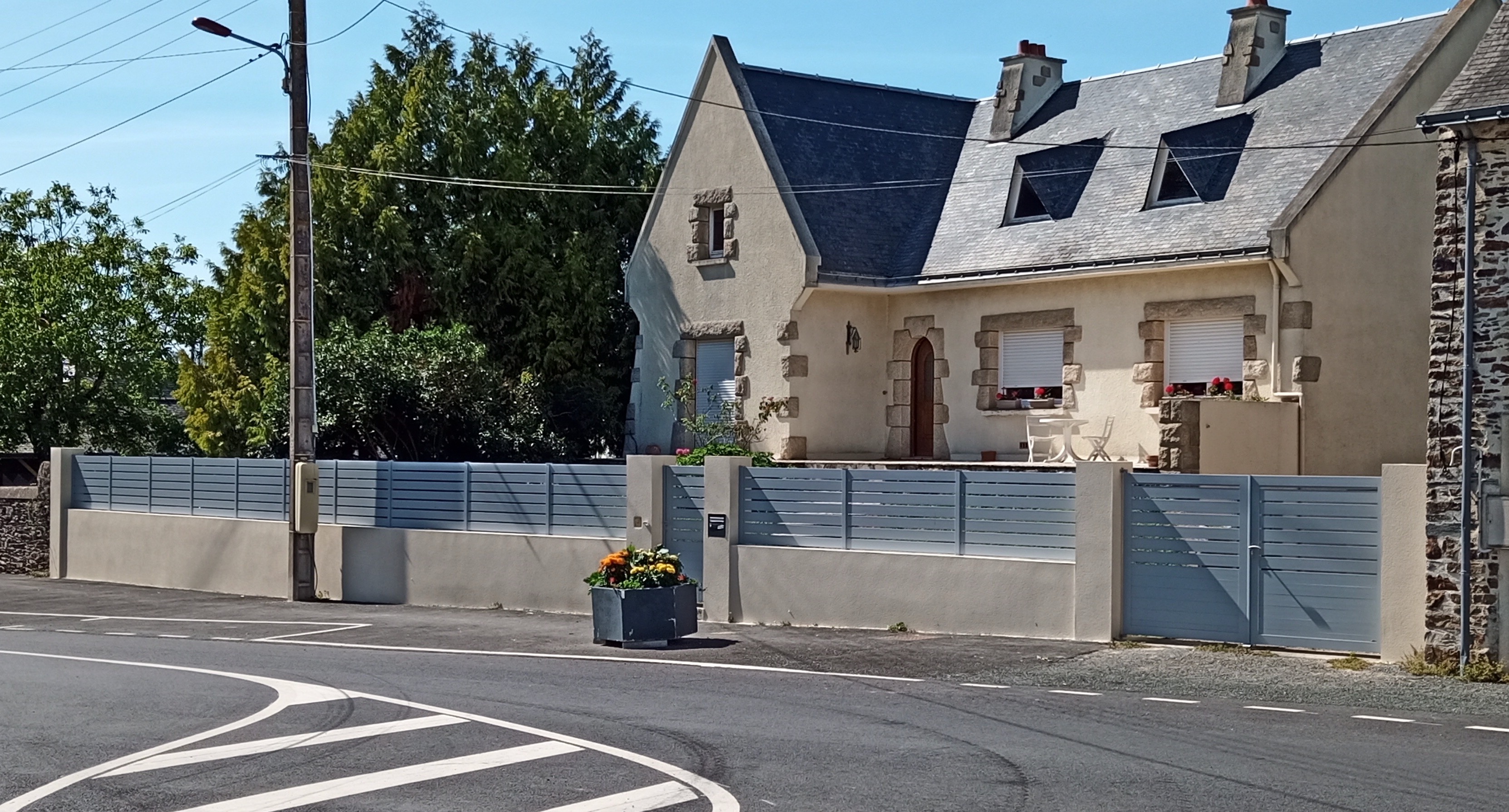 Maison bretonne avec portail bleu et jardin.