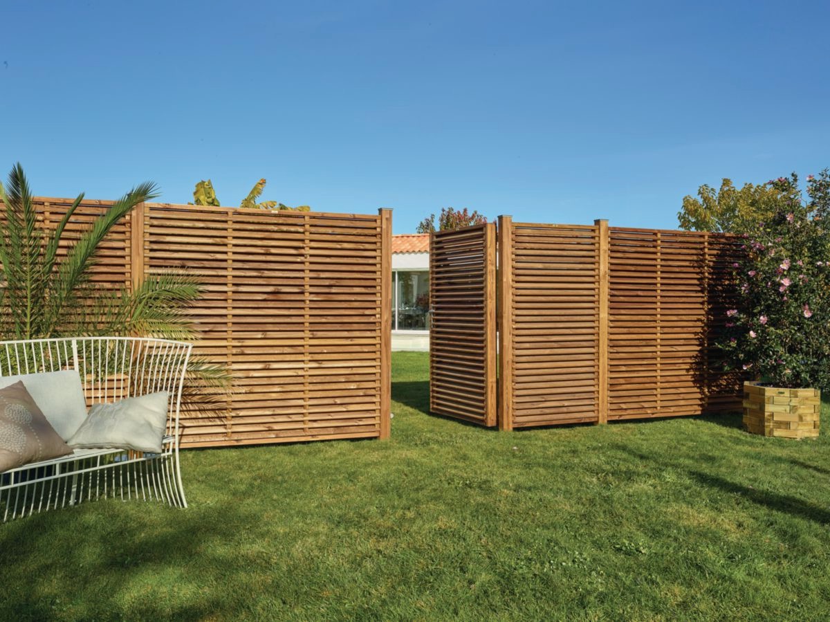 Clôture en bois moderne dans jardin verdoyant.