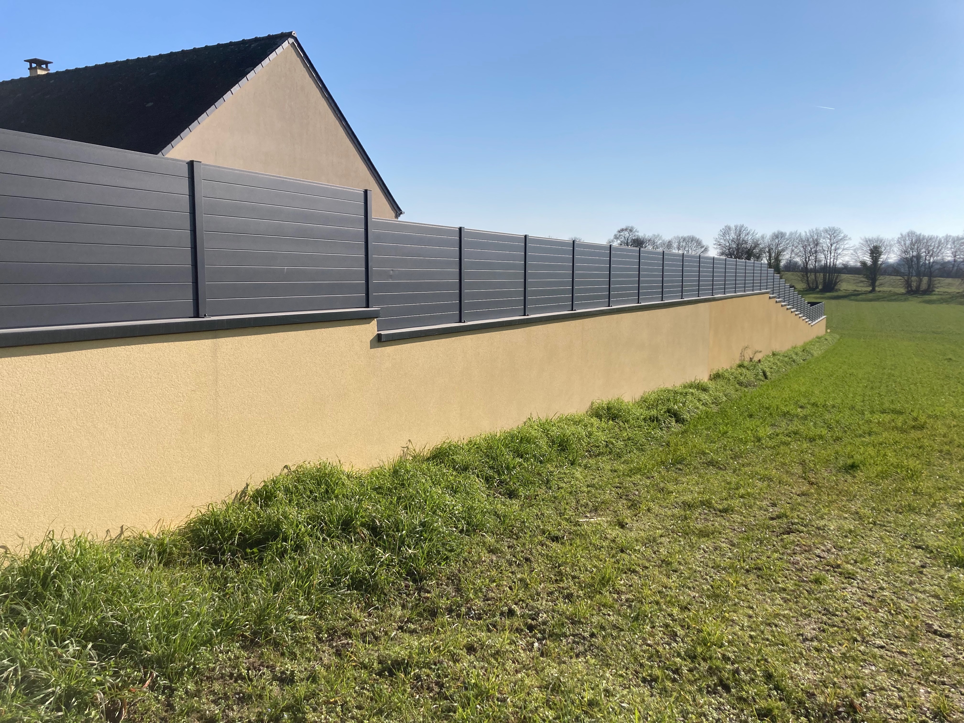 Clôture moderne et maison avec panneaux solaires.