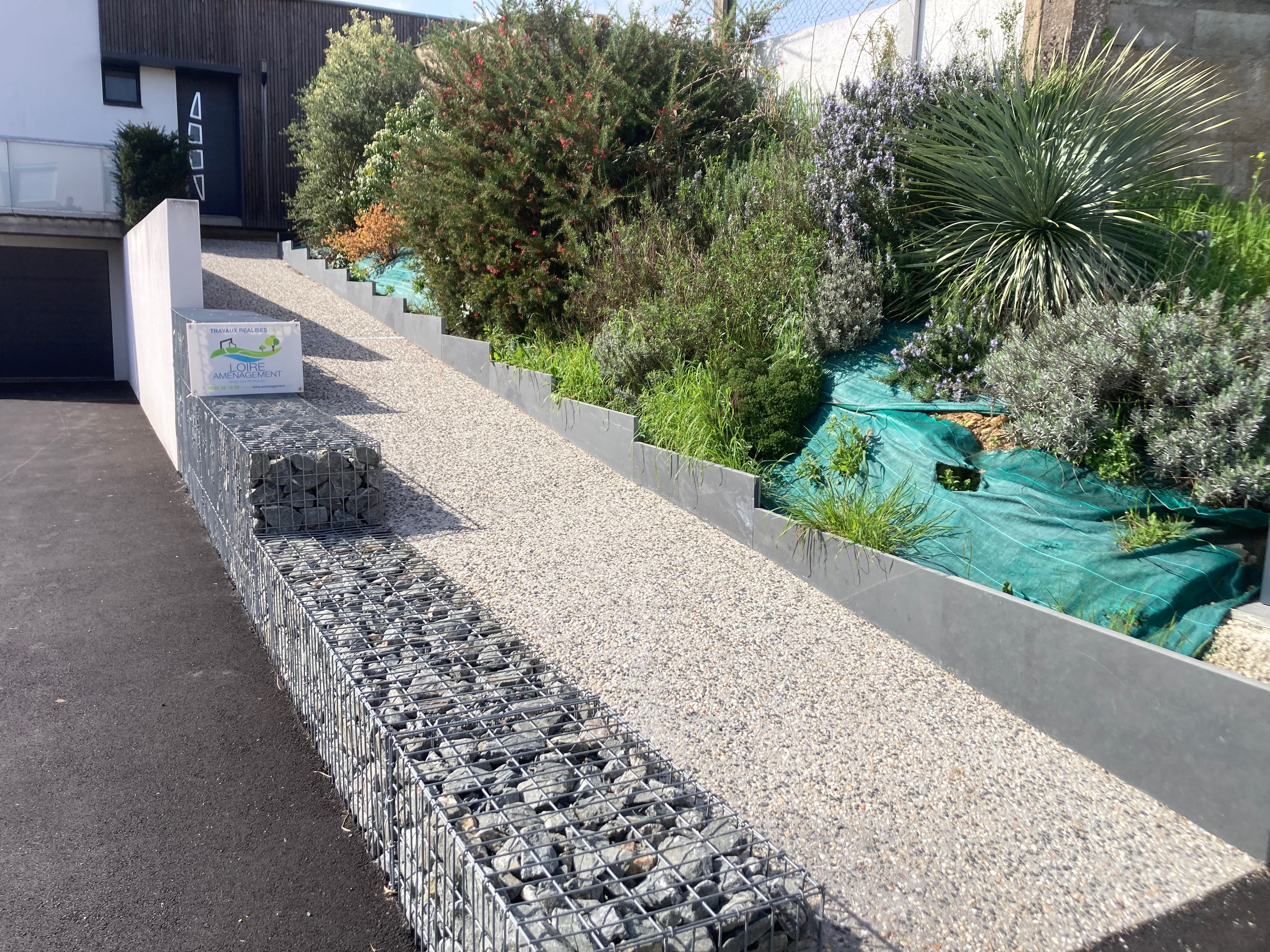 Jardin moderne avec gabions et plantes vivaces.