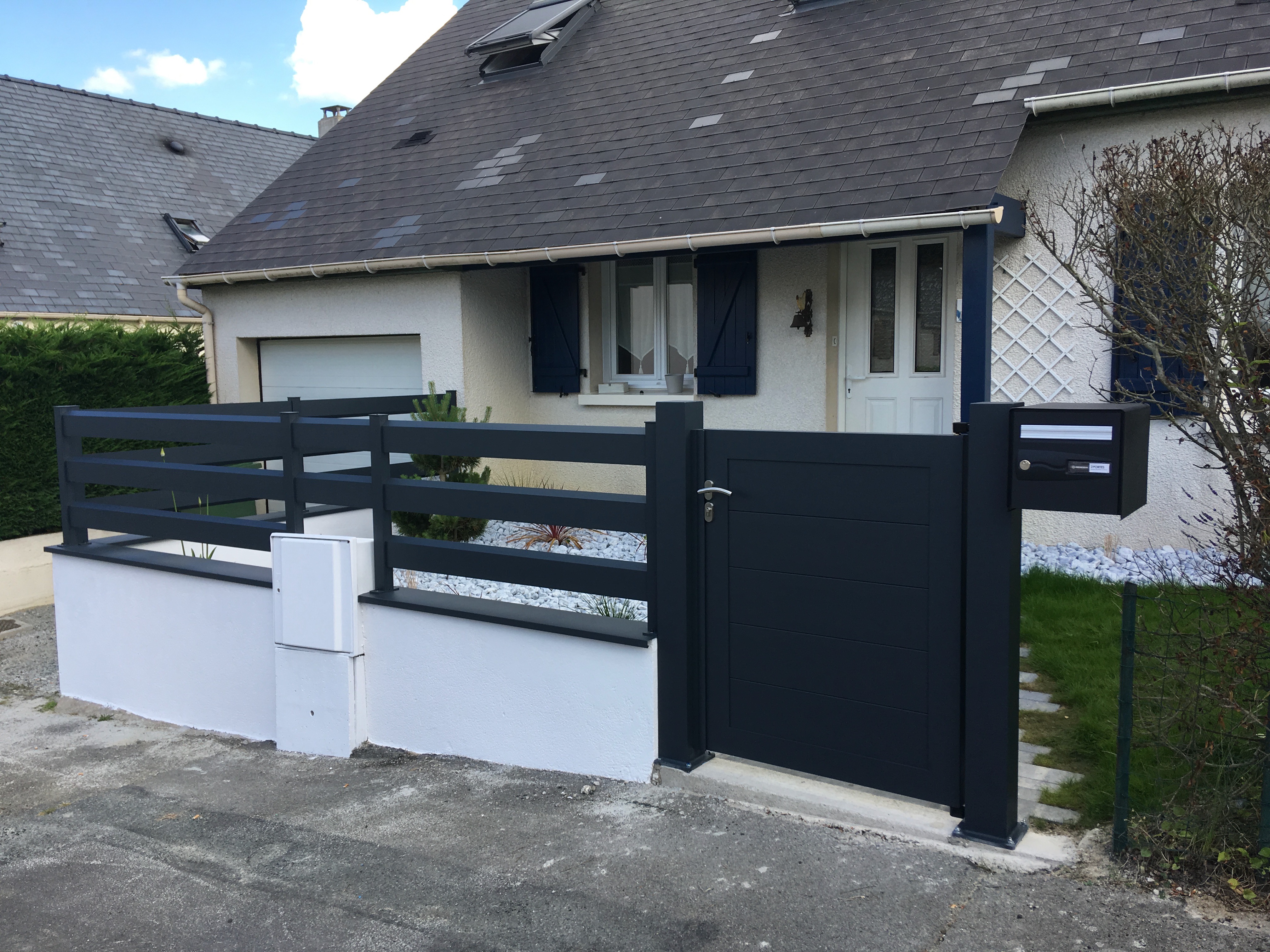 Portail moderne devant maison individuelle.